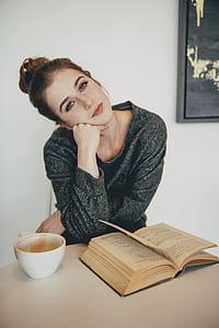 woman sitting in front of white mug and opened book thumbnail