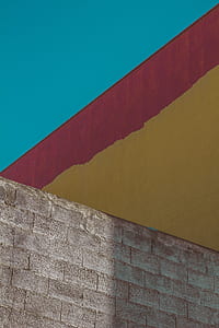 red brick wall beside yellow and red painted wall during daytime thumbnail