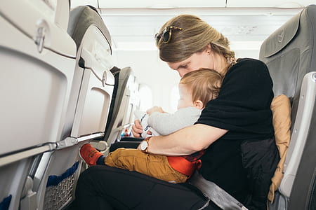 woman carrying baby sitting on airplane seat thumbnail