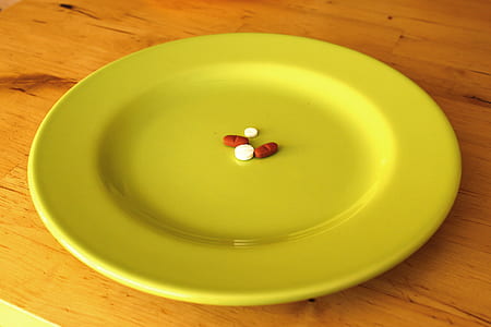 four red and white medication pills on round beige ceramic plate thumbnail