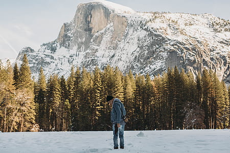 man standing on snow field with mountain on far side thumbnail