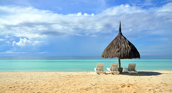 black hut covering white Adirondack chairs in front of beach thumbnail