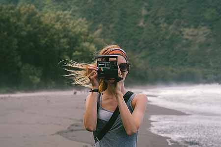 woman taking picture with black land camera in a beach during daytime thumbnail