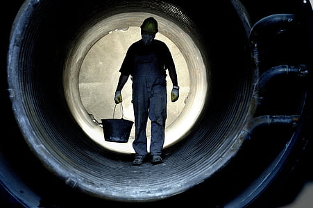 man carry black bucket inside black pipe thumbnail