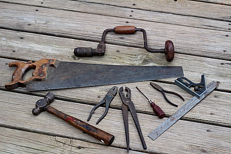 pliers, hand saw, and hammer on brown wooden surface thumbnail