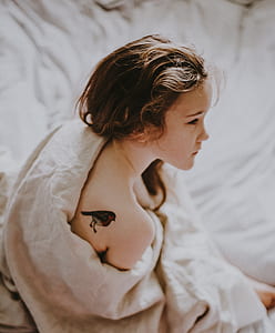 girl with bird tattoo on her right back shoulder wearing covered with blanket thumbnail