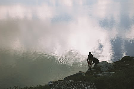 two men standing near calm water thumbnail
