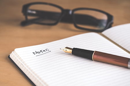 black framed eyeglasses above notebook with pen thumbnail