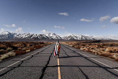 woman wearing scarf standing on road near glacier mountain at daytime thumbnail