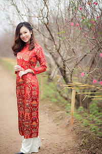 Woman in Red Crew-neck Long-sleeved Dress Near Bare Tree thumbnail