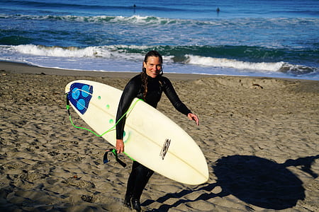 woman carrying surfboard near beach thumbnail