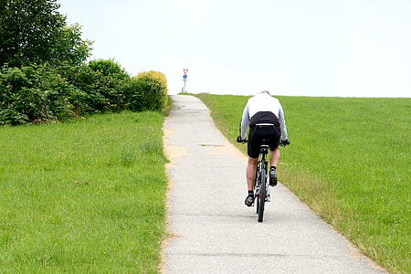 man riding bicycle between grasses thumbnail