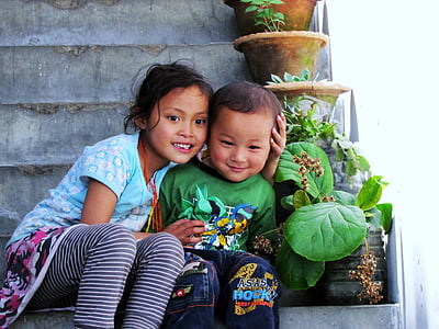 smiling girl and boy sitting on staircase beside plants during daytime thumbnail
