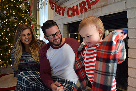 child with striped shirt holding plaid textile near man and woman thumbnail