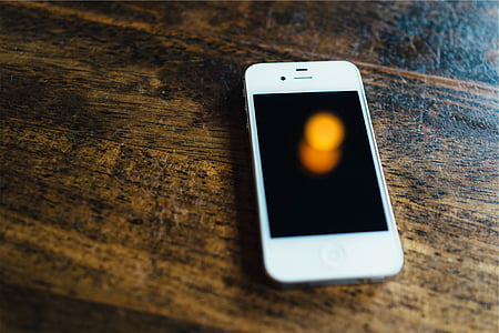 white iPhone 4 on brown wooden panel thumbnail