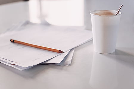white plastic disposable cup beside white paper and brown pencil thumbnail