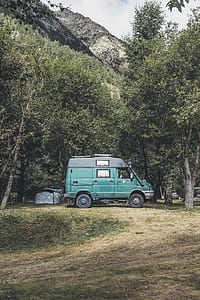 parked green minivan surrounded with trees at daytime thumbnail