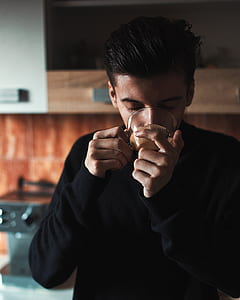 man in black sweater drinking in clear glass teacup thumbnail