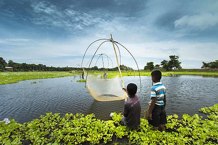 boy holding fishing net near body of water thumbnail