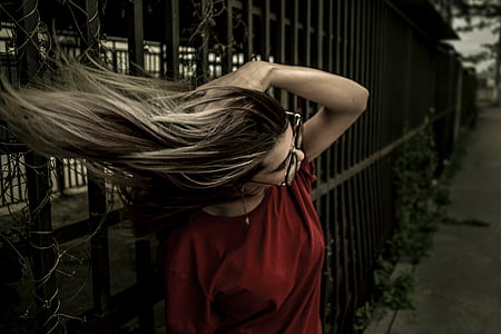 photo of woman wearing red shirt and black framed eyeglasses holding her hair thumbnail