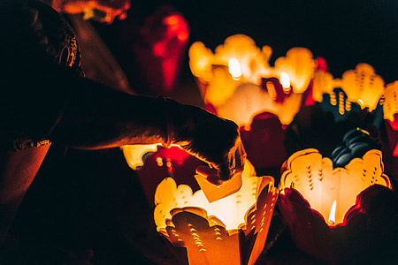 low light photography of person holding white paper near white basket with candle thumbnail