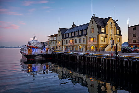 white cruiser ship docked beside wooden dock near beige concrete building thumbnail