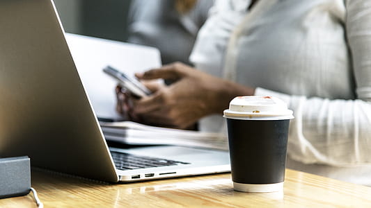 Black and White Plastic Coffee Cup Beside Gray Laptop Computer thumbnail