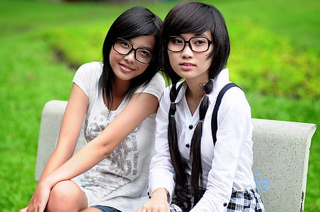two woman sitting on white concrete bench during daytime thumbnail