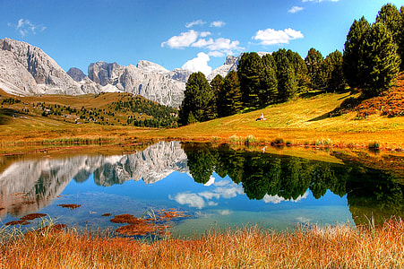 mountain and lake surrounded with green leaf tree under blue sky view during daytime thumbnail
