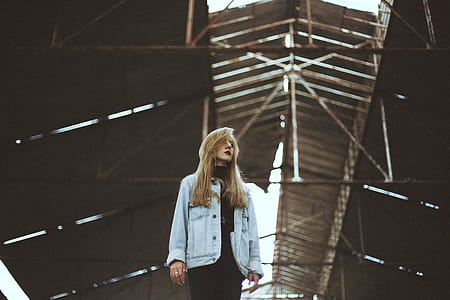 worm's eye view photography of woman standing under grey roof establishment thumbnail