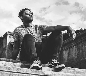 Grayscale Photo of a Man Wearing Pants and Vans Sk8-hi Sneakers thumbnail