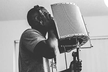 gray scale photography of man holding headset and microphone thumbnail