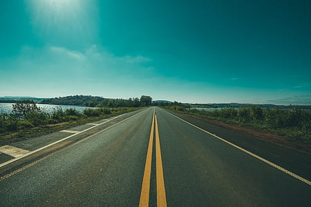 empty asphalt road under sun beside body of water thumbnail
