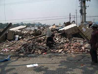 man sitting on concrete blocks of building debris during daytime thumbnail
