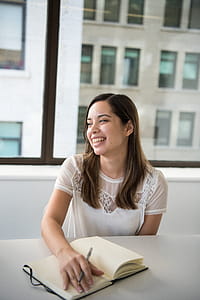 Woman Wearing White T-shirt Holding Notebook and Pen thumbnail