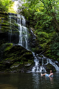 man on inflatable floater floating near waterfalls thumbnail