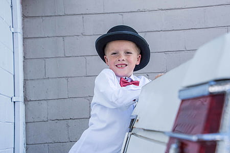 boy wearing white dress shirt standing beside vehicle thumbnail