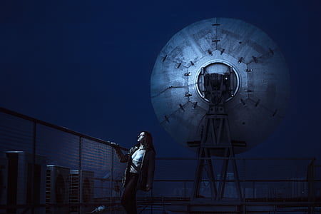 woman wears gray coat near satellite dish thumbnail