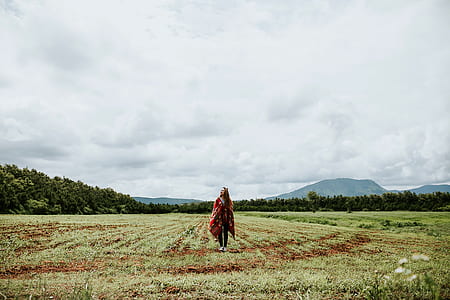 woman standing on green grass field under the white cloud at daytime thumbnail
