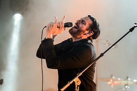 Man Wearing Black Collared Long Sleeve Shirt Holding Microphone thumbnail