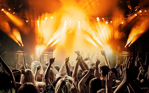 people raising hands infront of stage with band playing thumbnail
