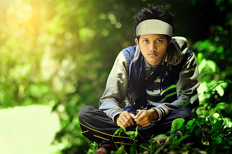 man sitting on green grass during daytime thumbnail