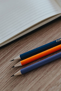 Notebooks with colourful pencils on a wooden desk thumbnail
