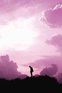 man on top of hill under white clouds thumbnail