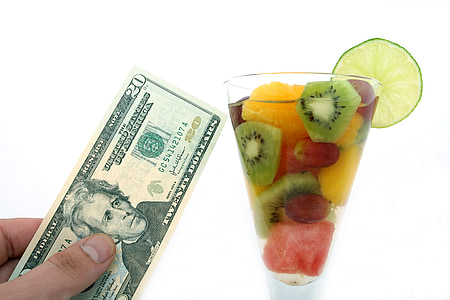 person holding 20 U.S. dollar beside cup with sliced fruits thumbnail