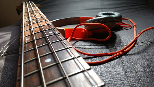 closeup photography of 4-string guitar over headset thumbnail