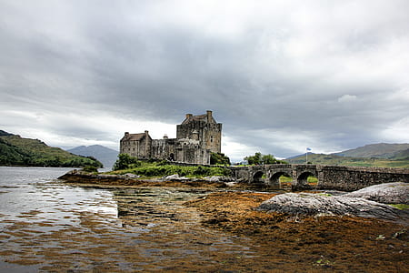 beige building near body of water under gray clouds thumbnail