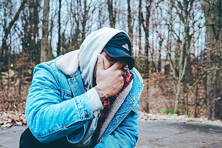 man in blue denim jacket standing near tree during daytime thumbnail
