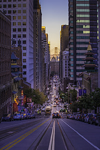 cars travelling in city with high rise buildings during daytime thumbnail
