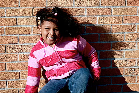 girls crouching near brown brick wall thumbnail